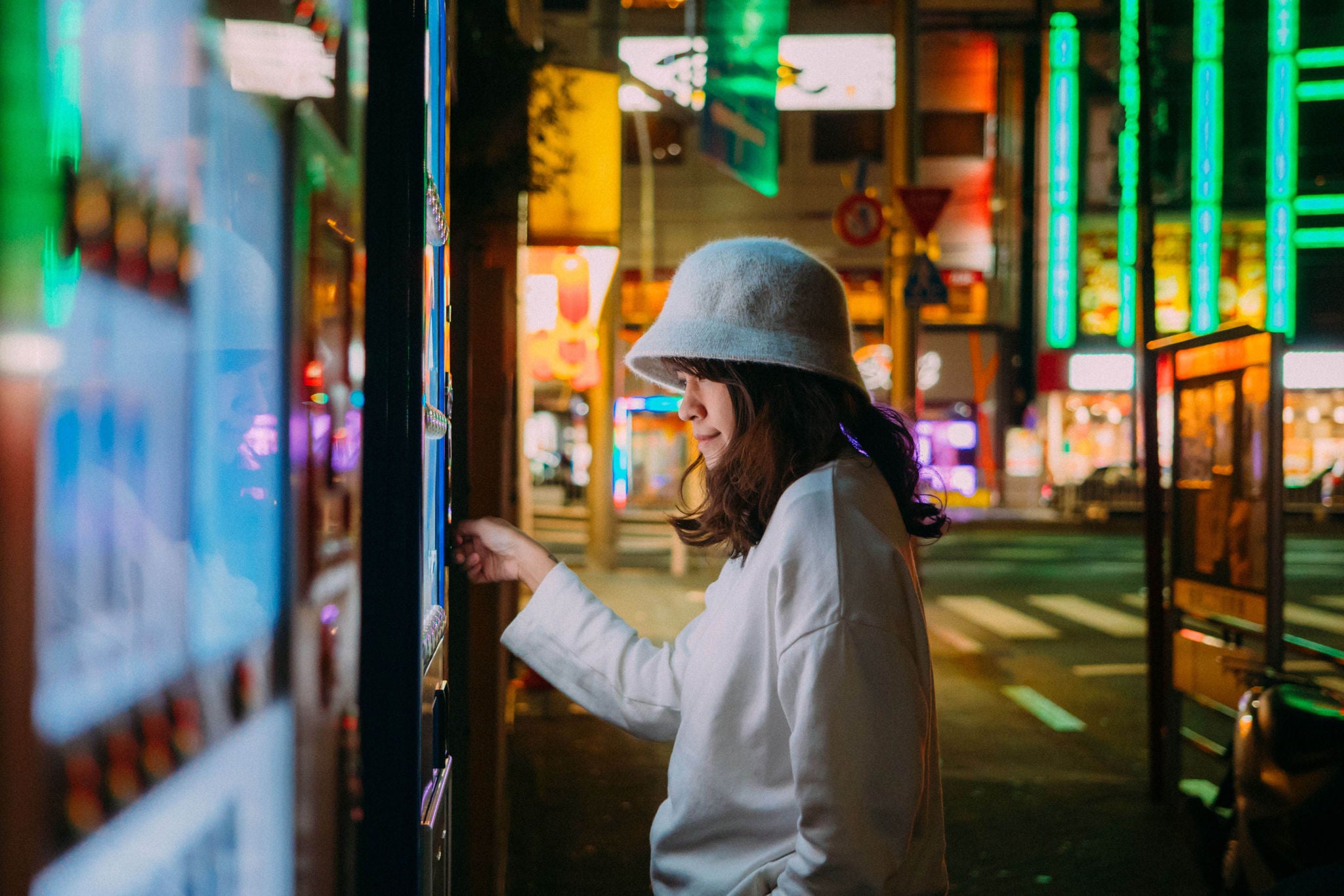 Asian woman paying with smartphone to vending machine.