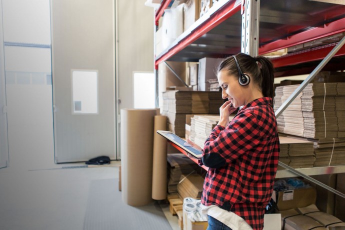 Women with headset and tablet in warehouse
