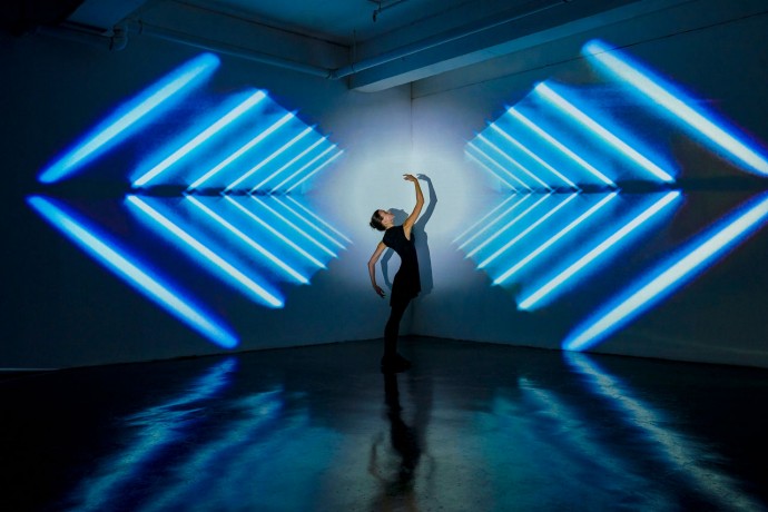 Girl dancing in a studio with graphic patterns projected onto wall behind